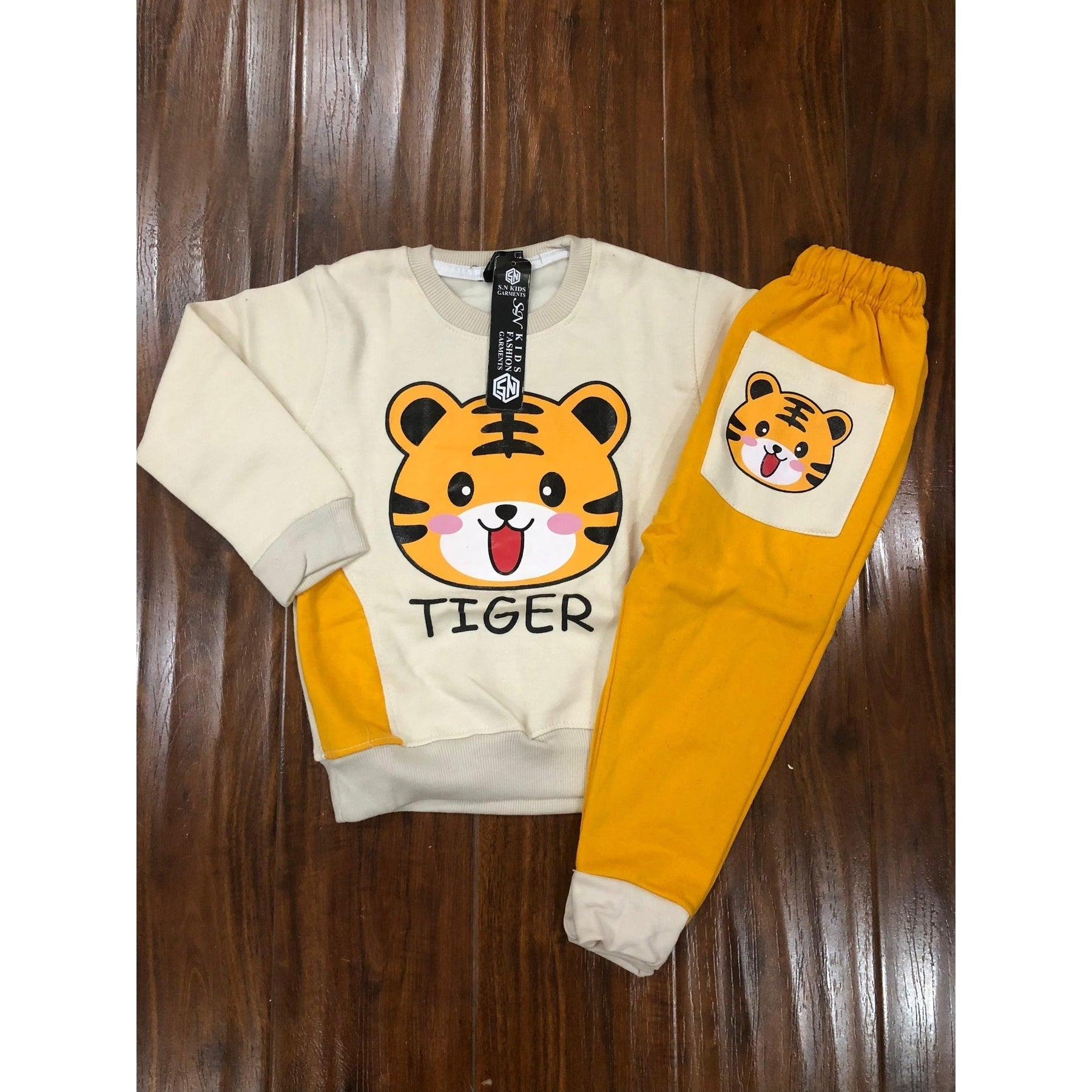 Children's outfit with a tiger-themed sweatshirt and pants on a wooden surface