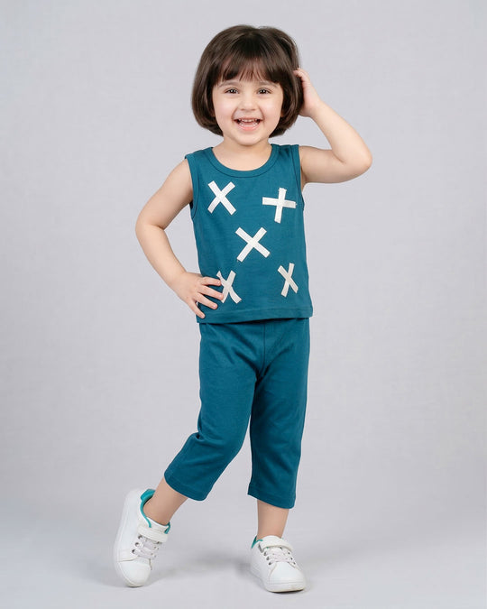 Child wearing a teal sleeveless top and capri pants with white cross patterns on a gray background