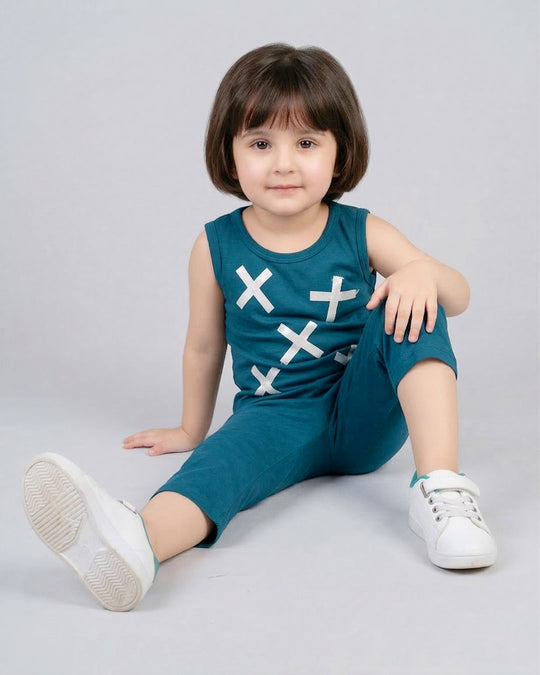 Child wearing a teal sleeveless top and shorts set with white cross patterns on a gray background