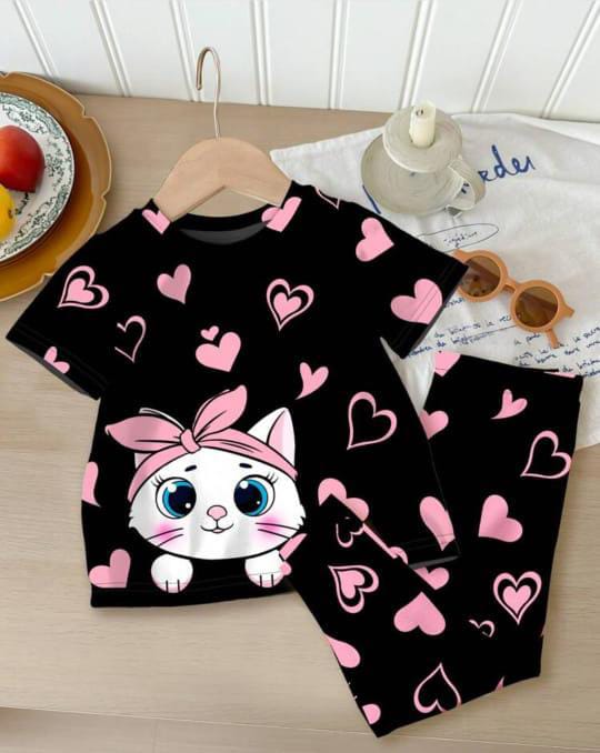 Black pajama set with a cartoon cat and pink hearts on a wooden table.