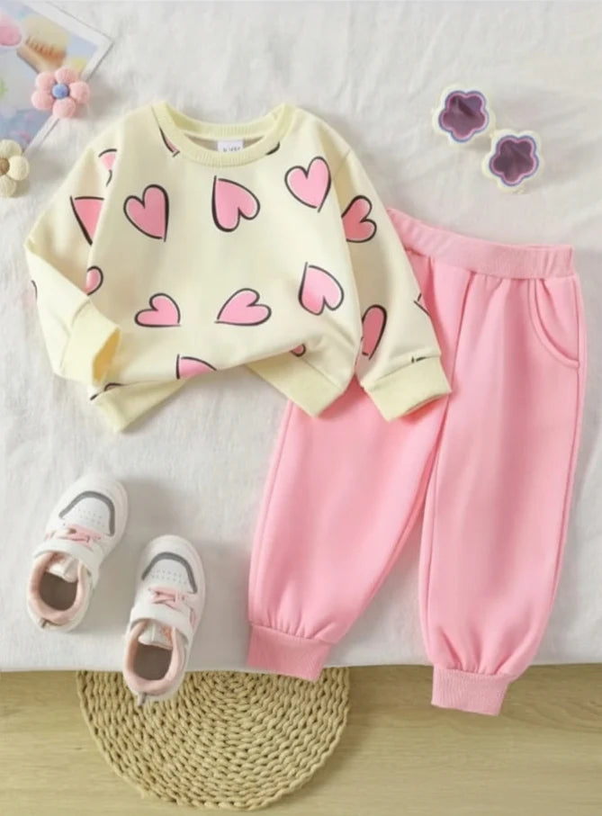 Children's outfit with yellow sweater and pink pants on a white surface.
