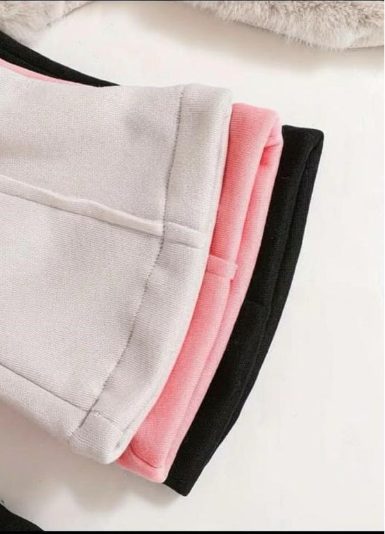 Three folded pairs of sweatpants stacked diagonally, showing light gray, pink, and black colors on a white background.