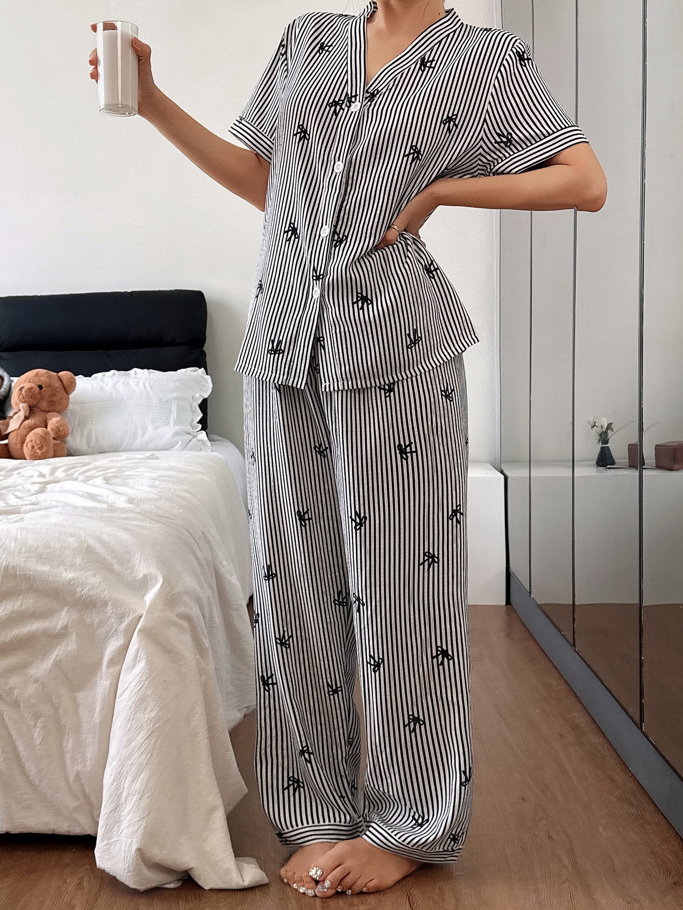 Person wearing a black and white striped pajama set in a bedroom.