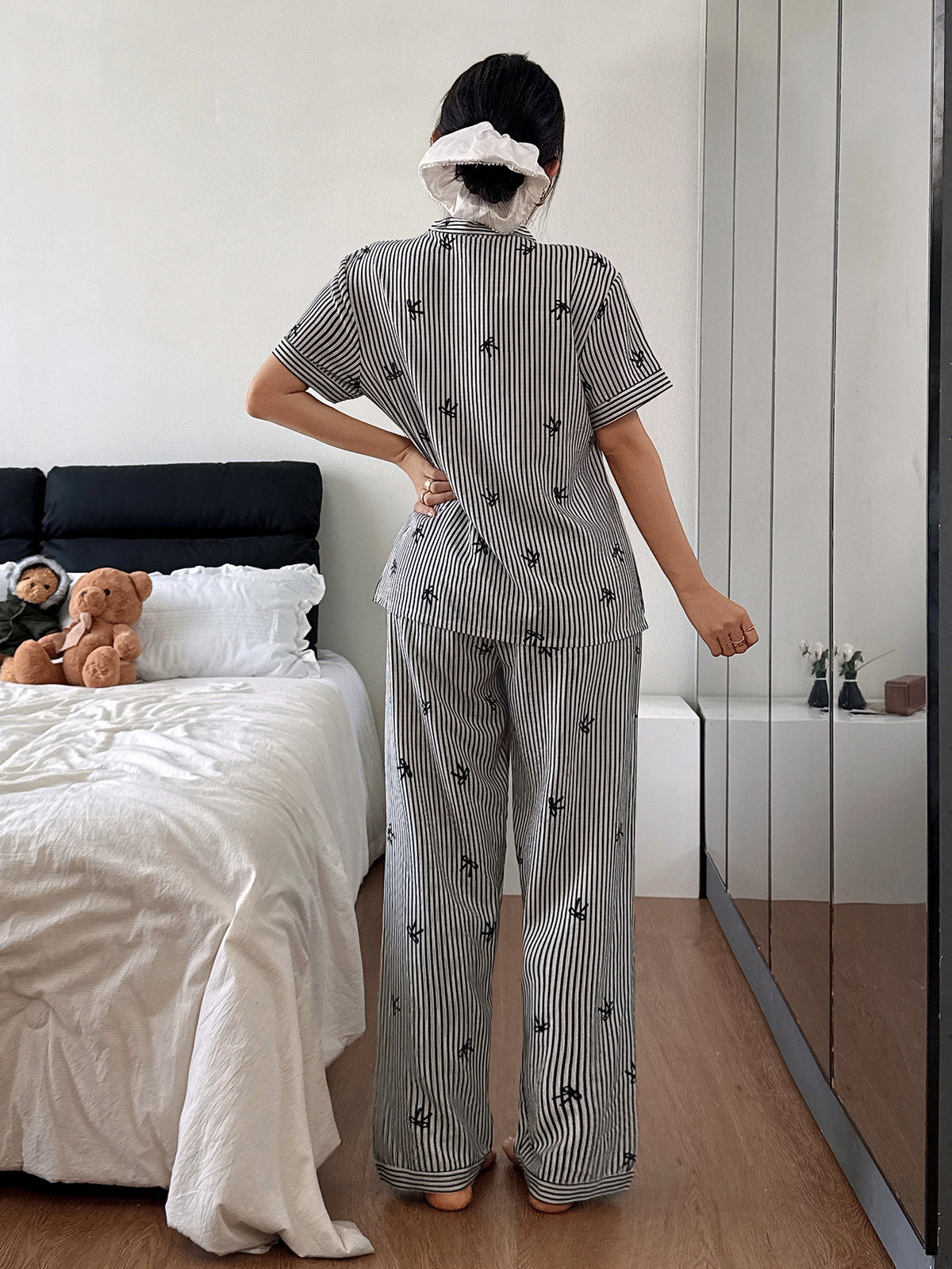 Person wearing a black and white striped pajama set in a bedroom.